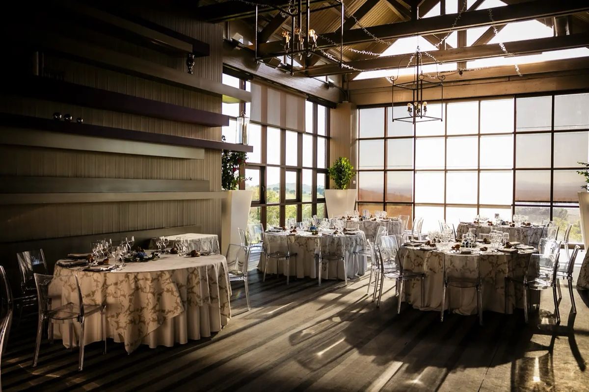Banquete con mesas redondas y ghost chairs en salón con ventanal