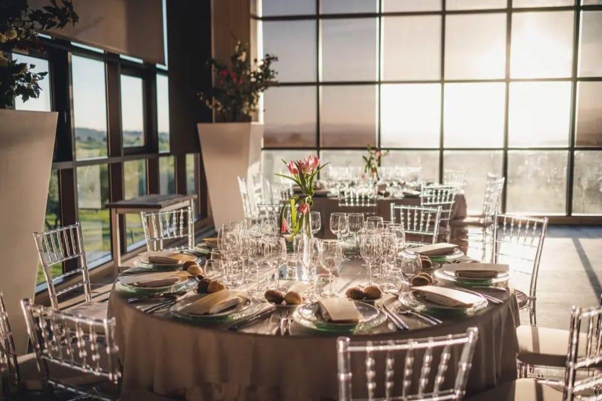 Detalle de mesa redonda montada con tulipanes, copas y luz dorada